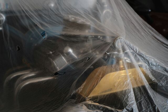 Studio still life of a camera and gear under a clear plastic sheet, lit from the side