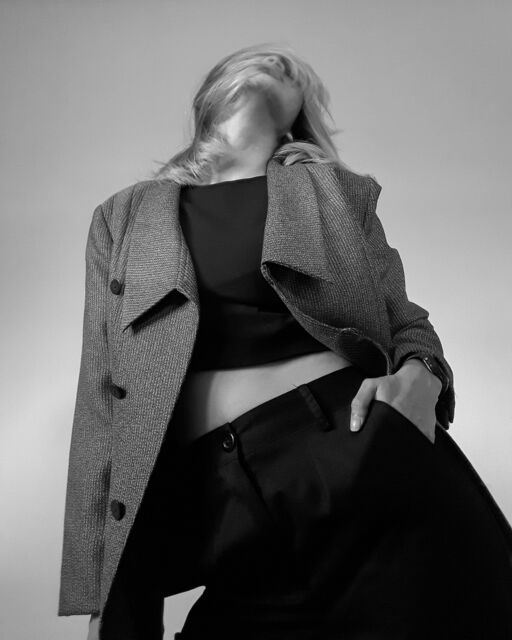 Black and white portrait of a woman in a grey blazer, face turned away