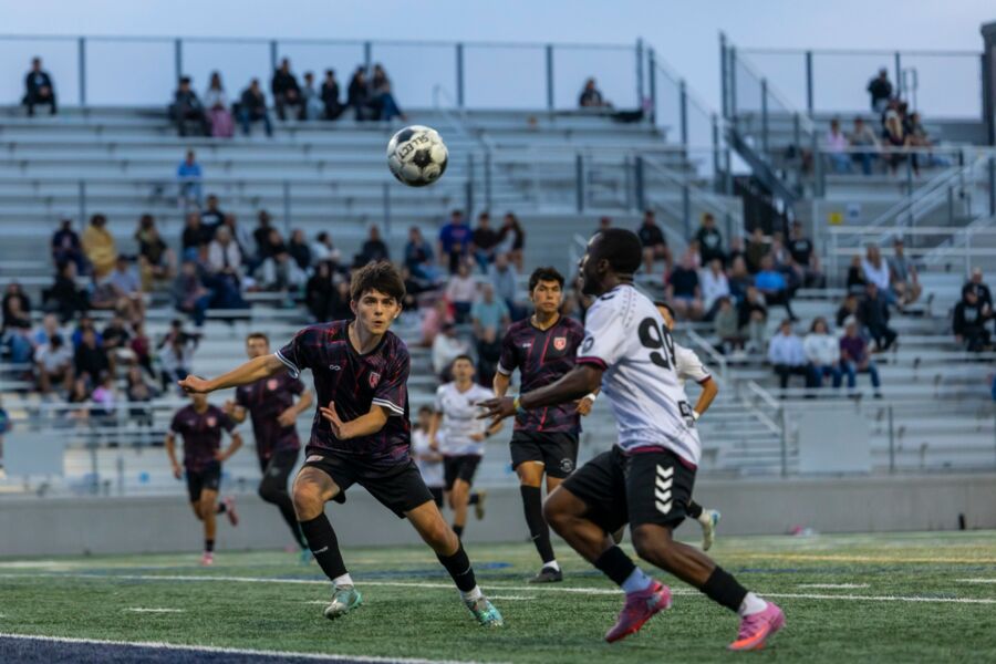 Youth soccer players chasing a ball in front of packed bleachers