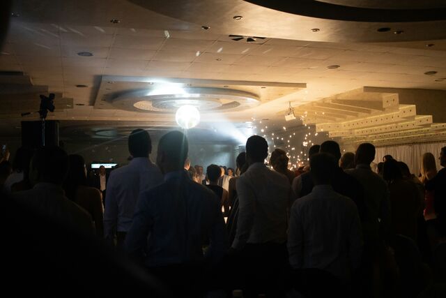 A dark wedding dance floor under a mirror ball, guests lit by a single spotlight