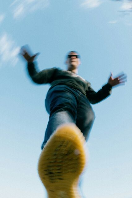 A skateboarder mid jump against a blue sky, motion blurred